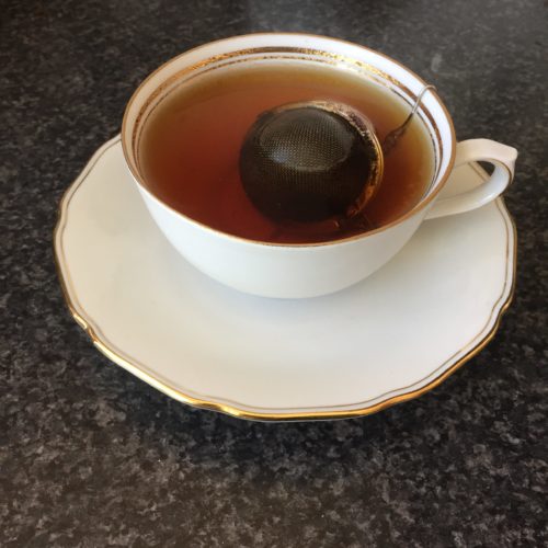 tea and tea ball in white cup